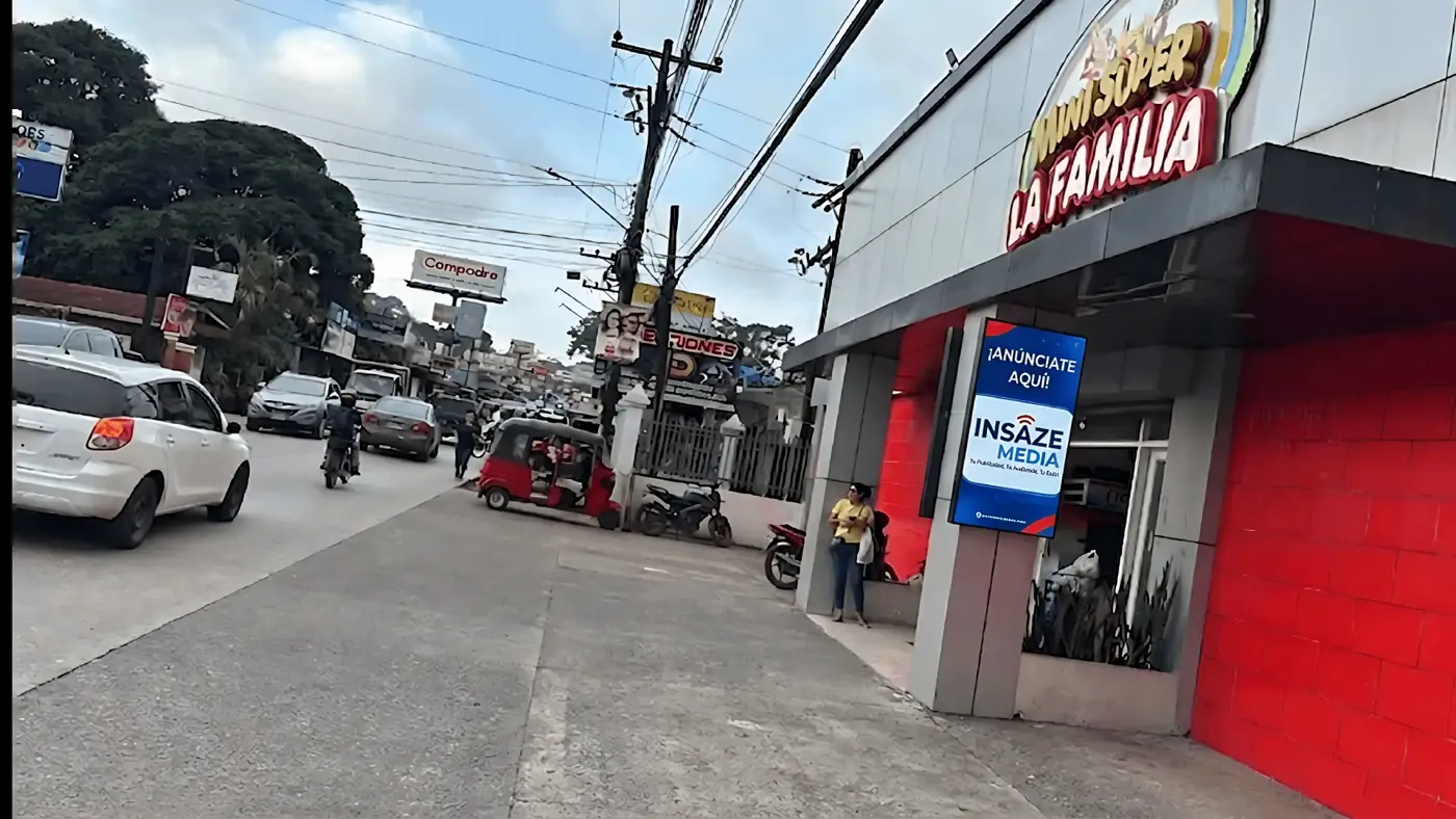 Pantalla publicitaria de INSAZE MEDIA frente a un minisúper en la calle principal de Peña Blanca, Honduras